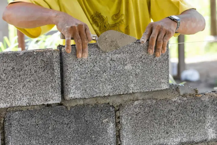 Murarz układa bloczki betonowe. Zastanawiasz się, ile bloczków betonowych na m2 potrzeba do budowy?